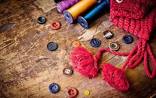 low light and close-up photograph of thread spools, tassels, and buttons HD wallpaper